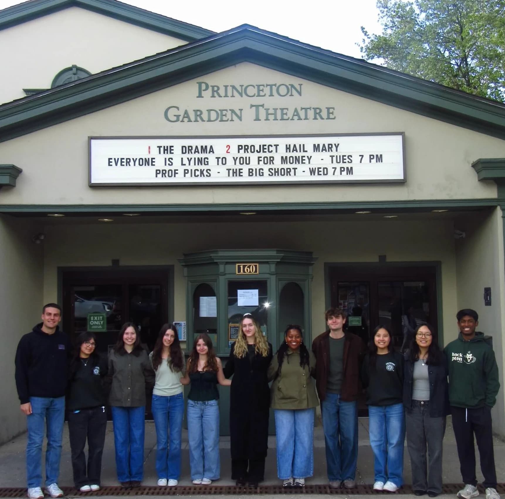 Eleven members of the USG Movies committee standing arm in arm under the marquee of The Garden Theatre
